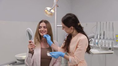 Diş hekimi ve hasta ile yapılan diş muayenesi neşe dolu gülümseme etkileşimlerini paylaşıyor. 