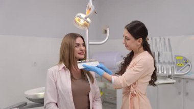 Diş hekimi, dişleri için en uygun gölgeyi seçerken hastaya dikkatli bir şekilde yardımcı olur..