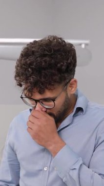 Modern ofis ortamında duygusal olarak bitkin görünen bir adam, stres, yorgunluk ve zihinsel gerginliği yansıtır. Sıklıkla iş ortamlarını talep etmekle ilişkilidir..