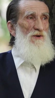 Uzun beyaz sakallı seçkin yaşlı bir adam yemyeşil, yemyeşil bir çevrede sakince duruyor. Bilgelik, yaşlanma, barış ve açık hava yaşam tarzı temaları için ideal. 