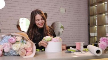 Yetenekli bir çiçekçi şık beyaz bir kapta zarif bir çiçek seçimi düzenler..