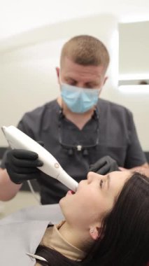 Hasta muayenesi sırasında modern oral tarayıcı kullanan bir diş hekimi. Dikey video. 