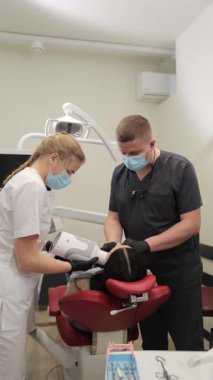 Modern bir klinikte dişçi muayenesi profesyonel bakım ile yapılır. Dikey video. 