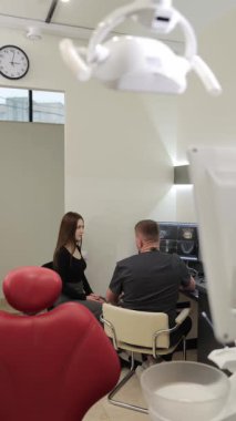 Dişçi muayene sırasında hastayla tedavi seçeneklerini tartışıyor. Dikey video.