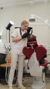 Dişçi modern diş kliniğinde kapsamlı bir kontrol yapıyor. Dikey video.