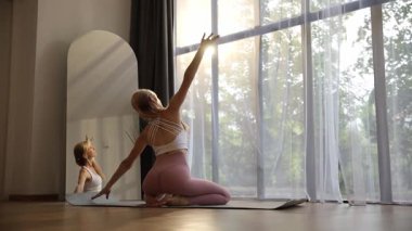 Huzurlu bir yoga seansını, güzel, güneşli bir odada, ilham verici bir ayna yansımasıyla yaşayın.