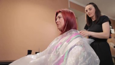 Çağdaş bir kuaför ortamında, yetenekli bir stilist müşteriye saç hazırlıklarında ustalıkla yardımcı olur.