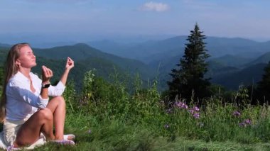 Huzurlu ve huzurlu bir sahne. Bir kadın, nefes kesici dağ manzarasının ortasında derin bir meditasyon yapıyor.