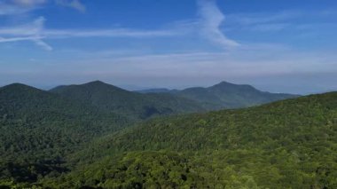 Hava fotoğrafçılığı, doğanın güzelliğini vurgulayarak, parlak, bulutsuz gökyüzünün altında genişleyen yeşil dağları yakalar..