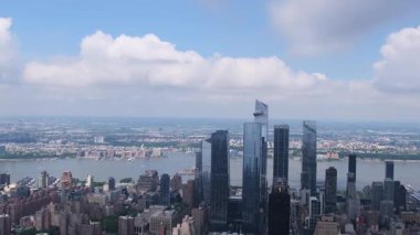 New York şehrinin dinamik hava manzarası nehir boyunca berrak gökdelenler, canlı ve hareketli bir şehir manzarası ile çevrili.