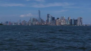New York şehri gökyüzü açık mavi gökyüzü ile parlak bir günde görkemli bir şekilde suyun üzerinde yükselir..