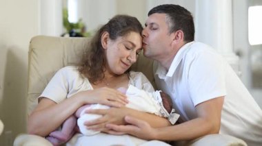 Sıcak bir ev ortamında yeni ebeveynler ve sevimli bebekleri arasında paylaşılan yürek ısıtan ve sevgi dolu bir an.