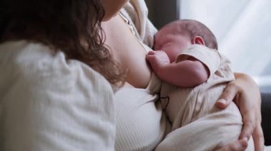 Huzurlu bir sahnede bir anne, yeni doğmuş bebeğini emziriyor ve derin anne bağlarını güzelce parlaklaştırıyor.
