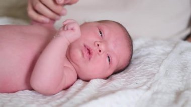 Sevimli yeni doğmuş bir bebek nazikçe bakılıyor, masumiyet ve samimiyet gösteriliyor. Aile ve ebeveynlik teması için mükemmel.