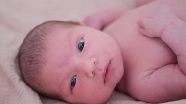 Yumuşak bir battaniyeye sakince uzanmış saf masumiyeti ve doğal güzelliği yakalayan yeni doğmuş bir bebeğin iç açıcı görüntüsü..