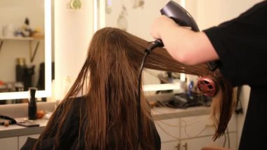 Profesyonel stilist, saç kurutma ve şekillendirme işlemine başlamadan önce uzun düz saç tarama ve kesim için tarak kullanır..