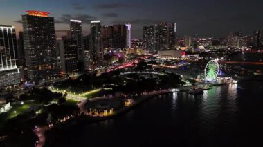 Alacakaranlıkta Florida şehrinin ufuk çizgisi, sıcak akşam ışığı ve dramatik tropikal bulutlar, drone hava çekimi.