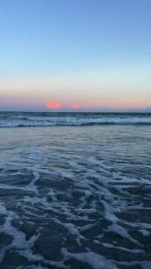 Deniz veya okyanus kıyısındaki gelgitin aşağı ve akışı. Deniz kıyısındaki suyun hareketi. Güzel deniz dalgaları akşam gökyüzünün arka planında.