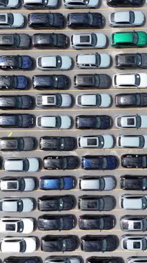 Bu, çok yoğun bir park alanının çeşitli renk ve modellerde sayısız araçla dolu bir genel görünüşü.