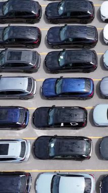 Düzenli sırada dizilmiş çeşitli araçlarla dolu hareketli bir otoparkın yukarıdan çekimi.