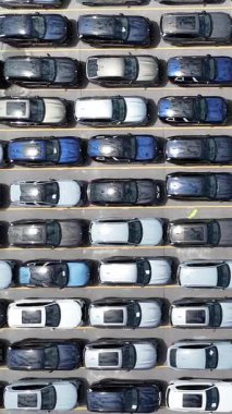 Küçük bir otoparkta çeşitli park edilmiş arabaları gösteren bir hava manzarası var.