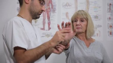 Eğitimli bir pratisyen hekim, klinik bir ortamda hastaların bilek sağlığını muayene eder.