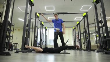 Kişisel antrenör, müşteriye çeşitli direniş bandı egzersizlerinde, hareketli bir spor salonunda ustaca rehberlik eder.