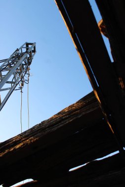 Fotoğraf, açık bir gökyüzüne karşı ahşap elementlerle yakalanan sütunu gösteriyor. Düşük açıdan çekilen çekim, yukarıdan tüm elementleri ortaya çıkaran eşsiz bir perspektif sunuyor..