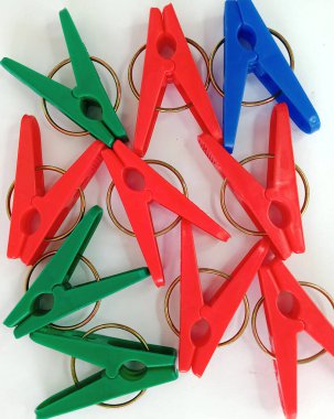 Plastikten yapılmış çamaşır mandallarının fotoğrafı, kırmızı, koyu yeşil, koyu mavi, beyaz arkaplan, güneşte kuruyan giysileri iğnelemek için kullanılır.