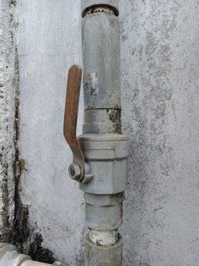 Su musluğunun açık pozisyondaki fotoğrafı, duvara dikey konumda bağlanmış, borudaki su kanalını açıp kapatmak için işlevler görüyor, renk solmaya ve soyulmaya başlıyor, kirli görünüyor