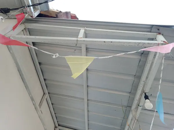 Demir çatıda asılı kırmızı, sarı, pembe ve mavi bayraklar, Endonezya 'nın bağımsızlık gününün önceki kutlamaları, aşağıdan çekilmiş fotoğraflar.