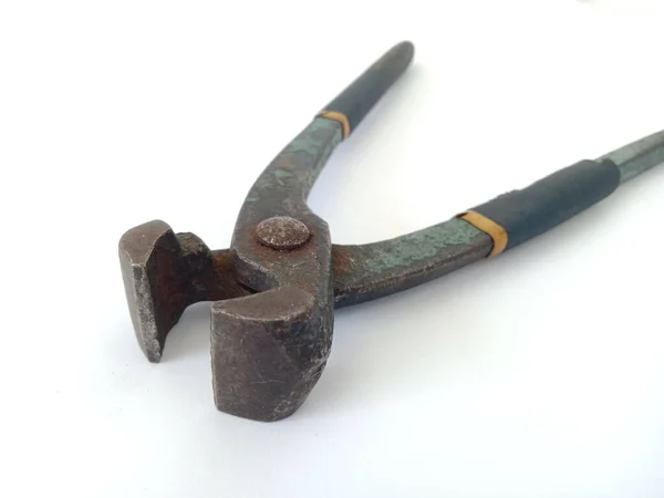 Demirden yapılmış eski bir pensenin beyaz arka planındaki yakın plan görüntüsü ve sapı koyu mavi kauçuğa sarılı, paslı görünüyor ve kauçuk soyuluyor.