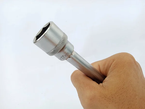 close up photo of a 17 mm socket wrench, made of high quality iron, for tightening and opening bolts on work objects or vehicles,held by a human hand on a white background