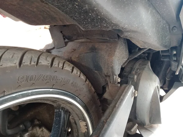 Close-up photo of a motorbike tire which is very dirty and dusty, looks very dirty from use and has not been cleaned