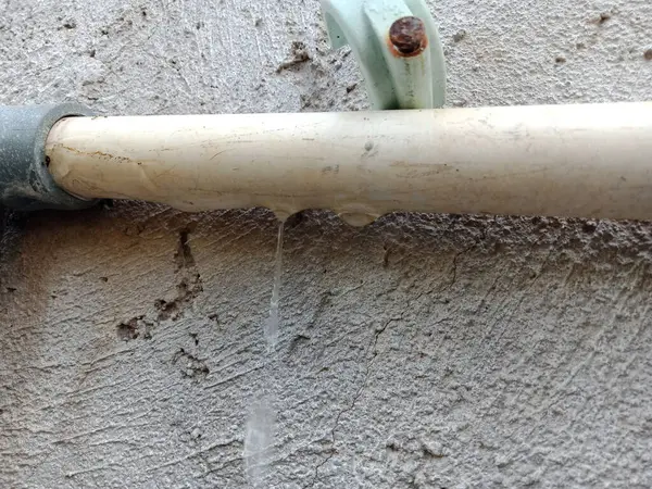 Picture of a water pipe that has a leak at the connection, so water drips between the pipe connections