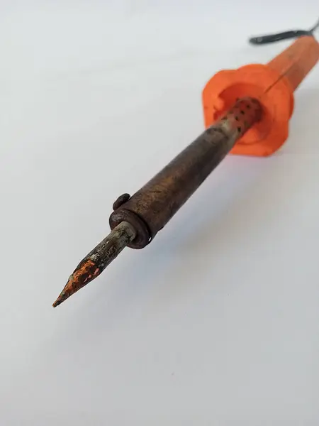 Turuncu saplı bir teneke lehim resmi. Kirli görünüyor ve temizlenmemiş bir sürü kabuğu var. Fotoğraf çekilmişti.