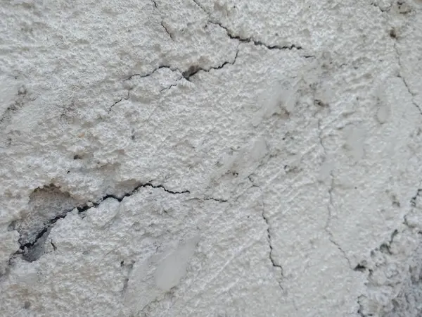 Küçük bir çatlağı olan beyaz bir duvarın yakın plan görüntüsü, sonuna kadar bölünmüş gibi görünüyor.