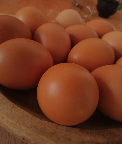 Tahta tepsiye yerleştirilmiş birkaç çiğ yumurtanın yakın plan fotoğrafı, stüdyoda çekilmiş bir fotoğraf.