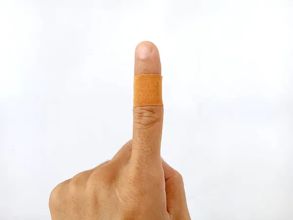 photo of injured index finger covered with plaster for first aid, picture taken in studio on white background