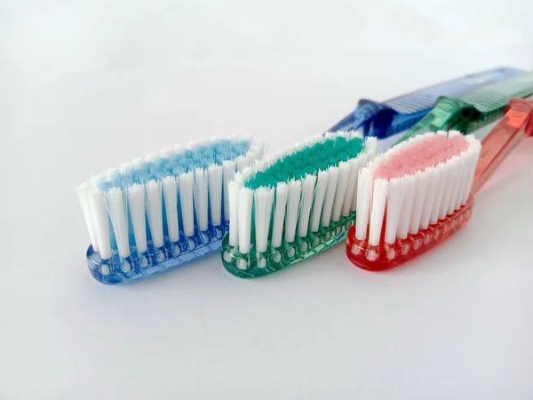 stock image close-up image of three toothbrushes, blue, green and red, isolated on a white background