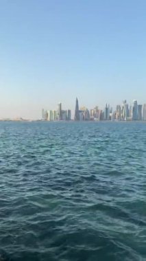 Gündüz vakti Katar, Doha 'daki West Bay' in deniz manzarası ve ufuk çizgisinin dikey kısa videosu