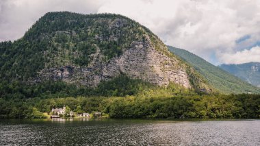 Alp Gölü 'nün kıyısındaki bir dağ Hallsttter' da öğleden sonra güneşiyle parlayan yağmur bulutları ile aydınlanır. Gölün kenarında bir ev.