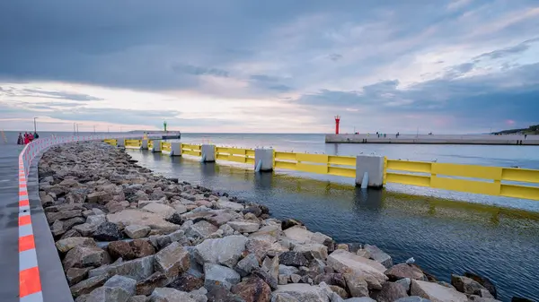Ön planda taşlı deniz feneri olan şehir limanı.