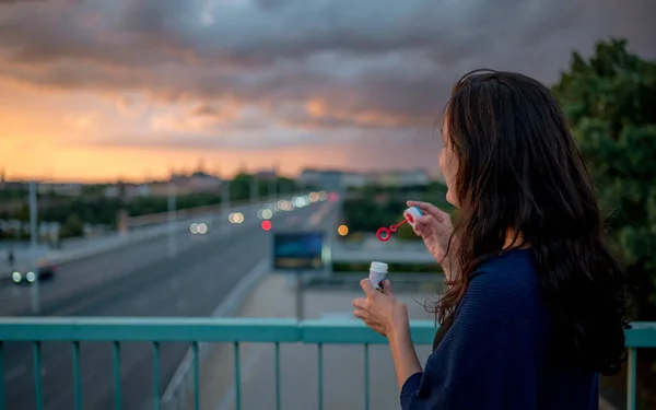 Akşam güneşinde kabarcık üfleyen bir kadın.
