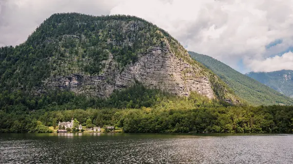 Alp Gölü 'nün kıyısındaki bir dağ Hallsttter' da öğleden sonra güneşiyle parlayan yağmur bulutları ile aydınlanır. Gölün kenarında bir ev.