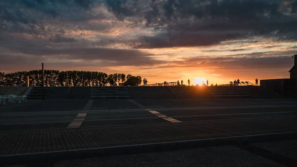 Gün batımında arka planda insanların olduğu bir manzara. Normandiya, Fransa