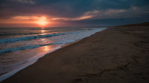 Atlantik üzerinde gün batımı, insanlar olmadan kumlu sahil.