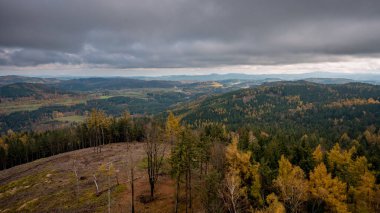 Yağmurlu bir günde renkli ağaçlarla sonbahar tepelerinin manzarası. 
