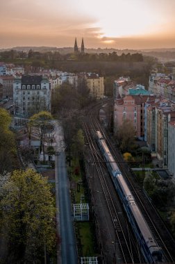 Bu görüntü Nusle Köprüsü 'nden, uzaktaki Vyehrad Katedrali' nin huzurlu günbatımı görüntüsünü yakalar. Hava, Sahra tozu parçacıklarından gelen eşsiz bir parıltıyla dolu. Prag siluetine mistik bir nitelik katıyor..