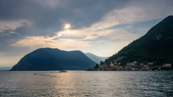 Lago d 'Iseo kıyılarına kurulmuş sakin bir köy manzarası. Arka planda dağlar ve manzarayı aydınlatan yumuşak bir akşam ışığı..